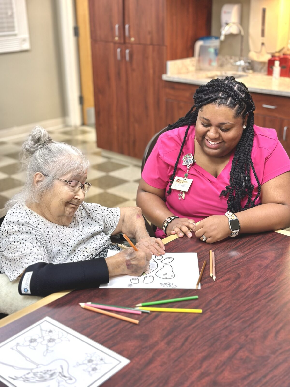 staff member painting a  with a senior female resident